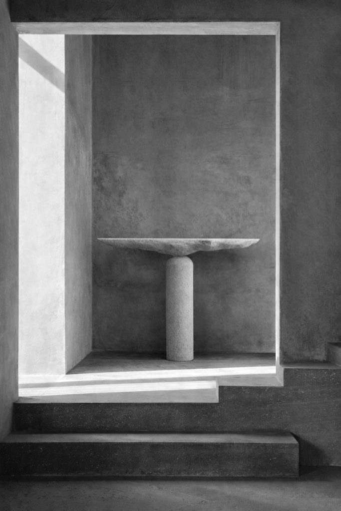 Sculptural stone pedestal table by Isac Elam Kaid with circular stone plane supported by a cylindrical column.