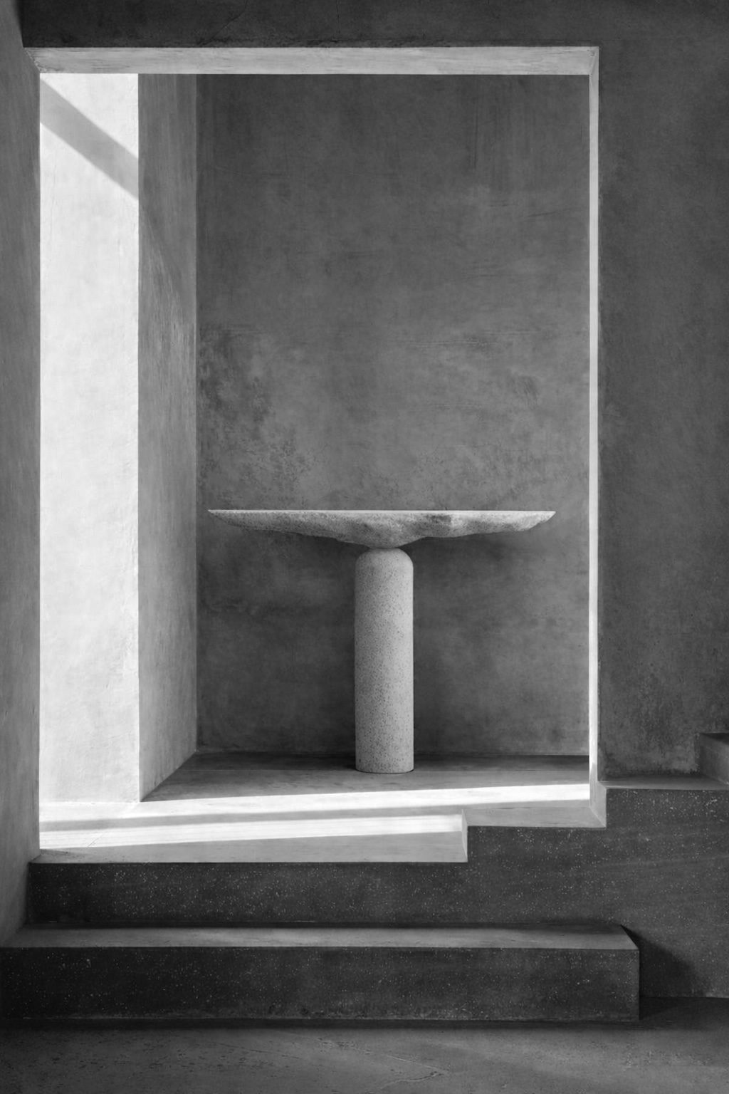 Sculptural stone pedestal table by Isac Elam Kaid with circular stone plane supported by a cylindrical column.