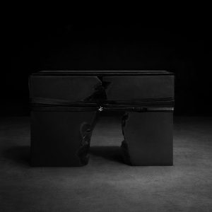 Monolithic fractured stone bench by sculptor Isac Elam Kaid bound with leather and silver hardware in a minimal studio setting.