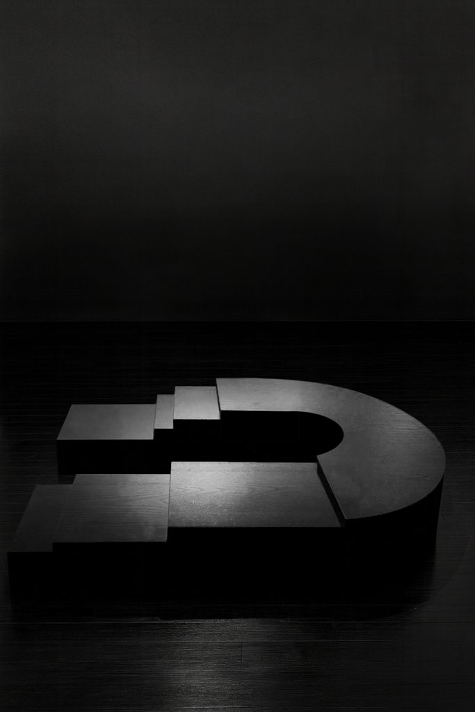 K2505 sculptural ebonized wood table by Isac Elam Kaid, a monolithic low table composed of laminated timber layers forming a stepped architectural mass.