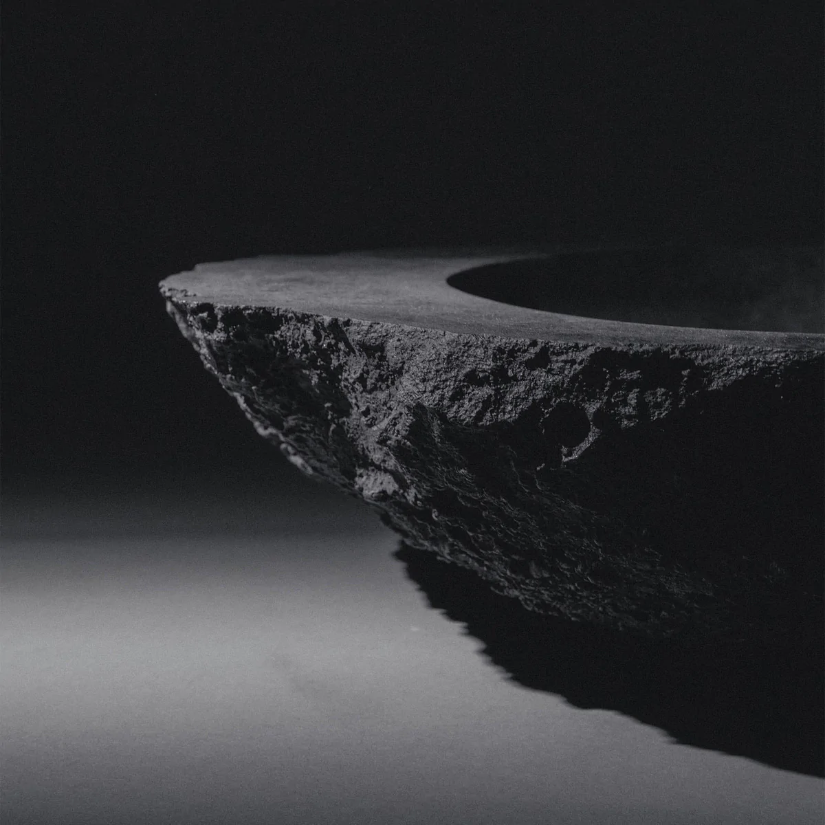 Blackened bronze sculptural vessel by Isac Elam Kaid with irregular eroded edge and circular basin form.